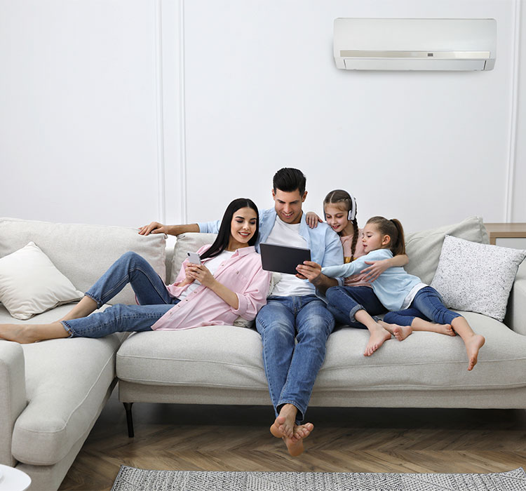 Happy family resting under air conditioner on white wall at home