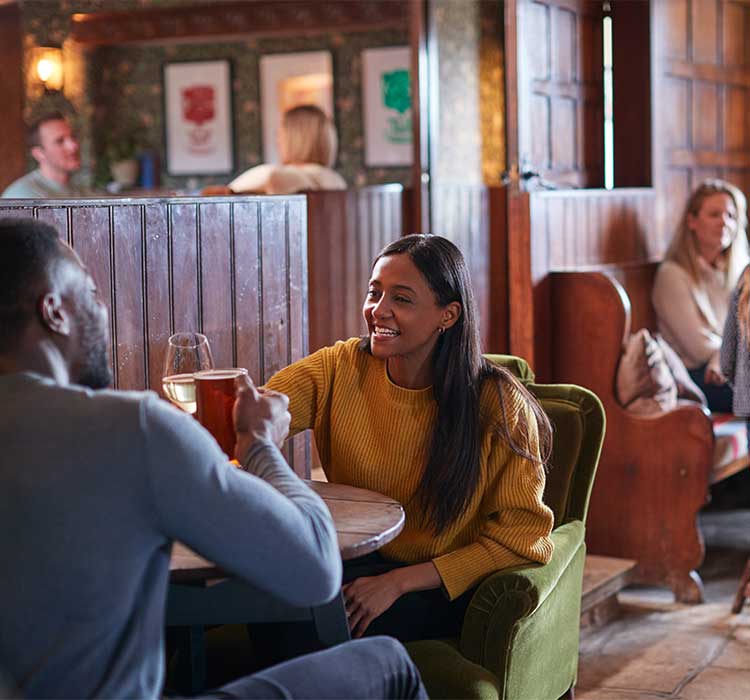 Couple Meeting For Lunchtime Drinks In Traditional English Pub Making A Toast