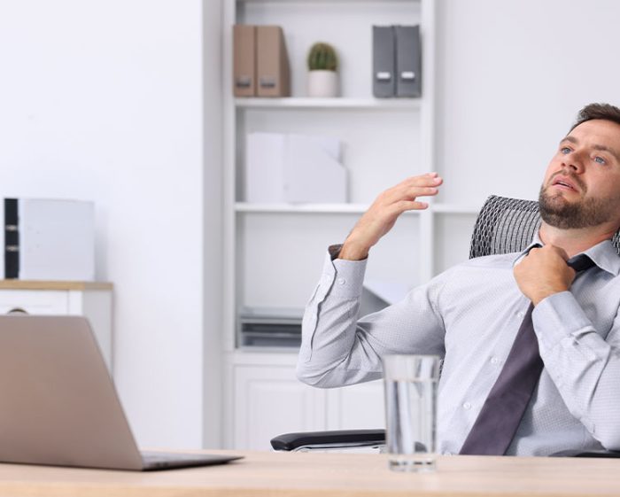 Downloaded Air conditioning. Man suffering from heat at workplace in office